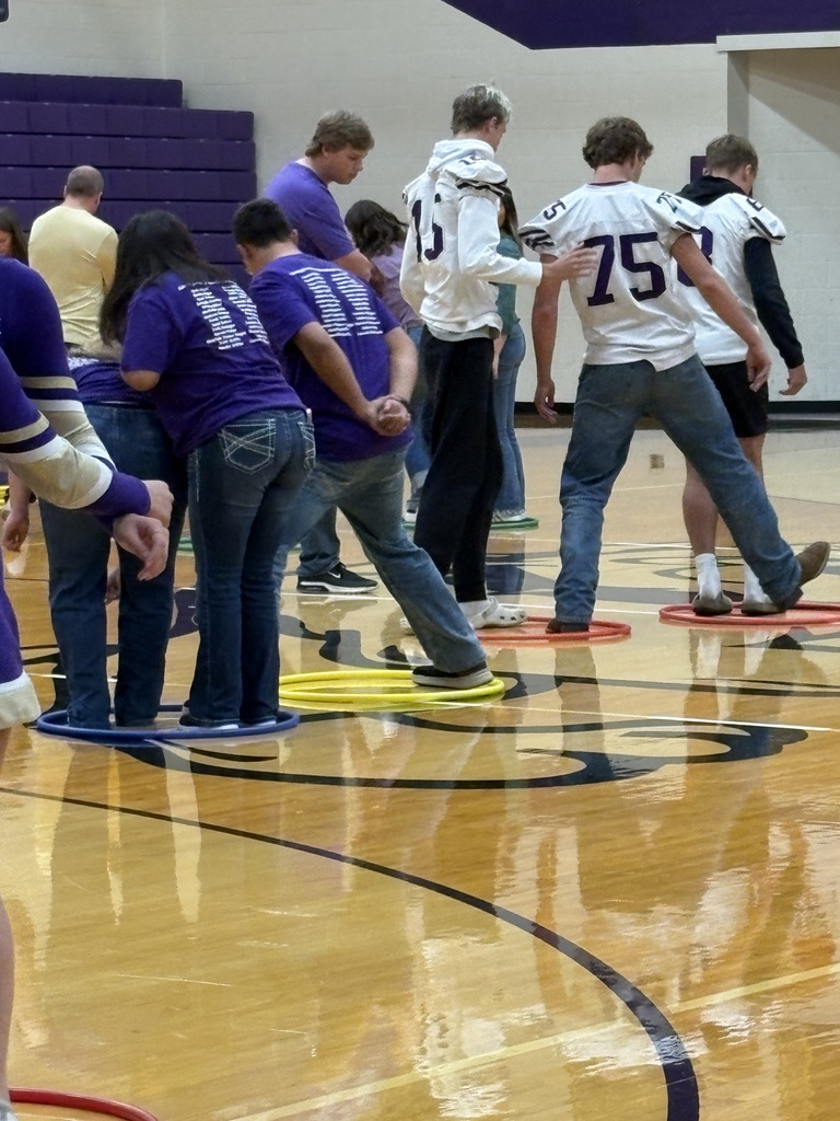 High school students standing in hula hoops on a gym floor