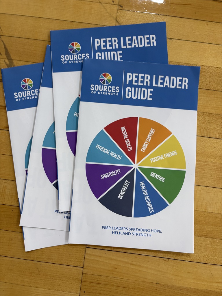 booklets on the gym floor with a rainbow color wheel and blue header at the top