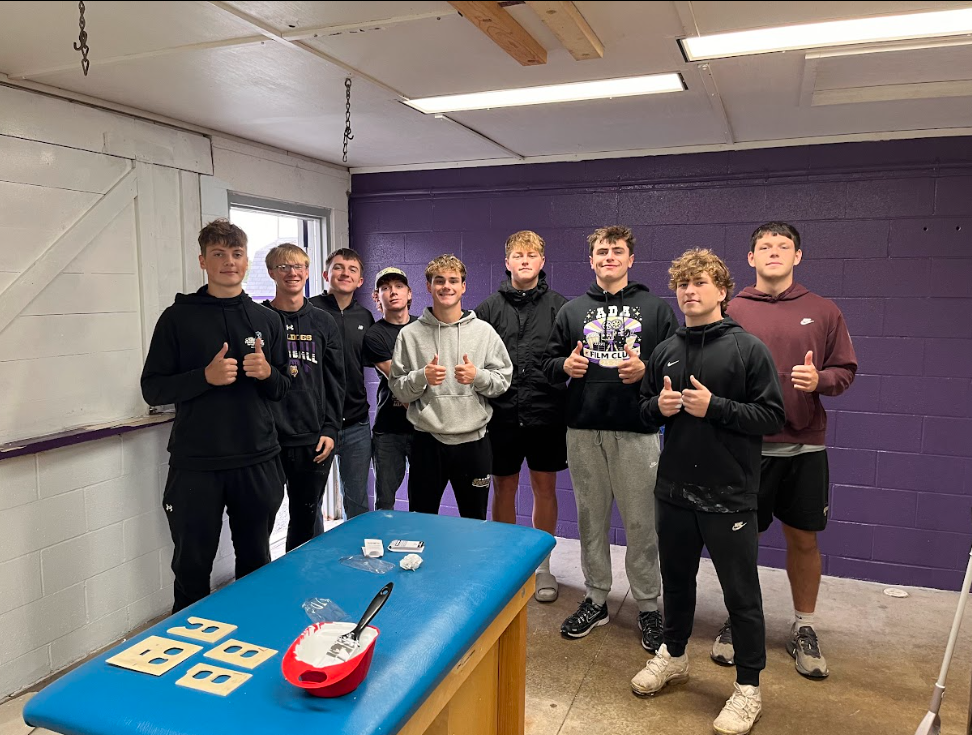 9 students with their thumbs up smiling at the camera