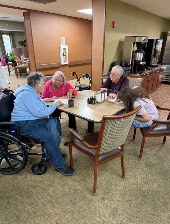 student with nursing home resident at a table
