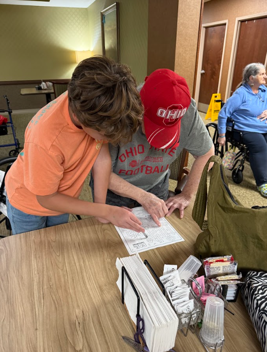 student with nursing home resident at a table