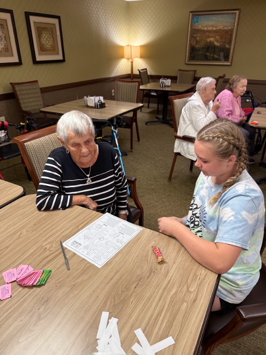 student with nursing home resident at a table