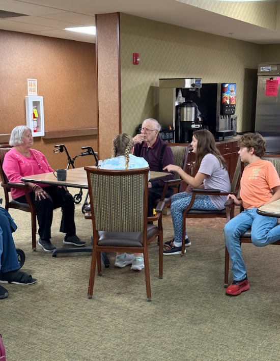 student with nursing home resident at a table
