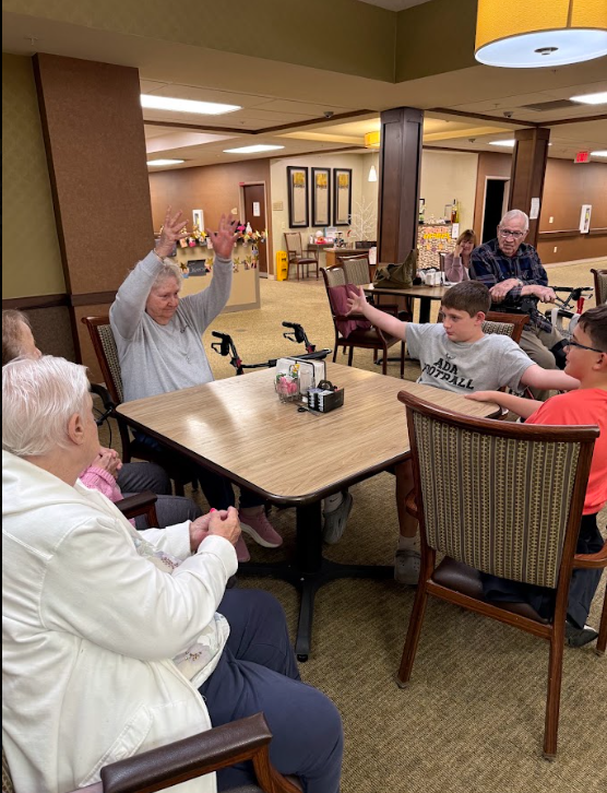 student with nursing home resident at a table