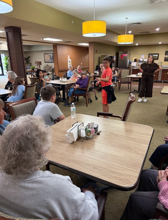 student with nursing home resident at a table