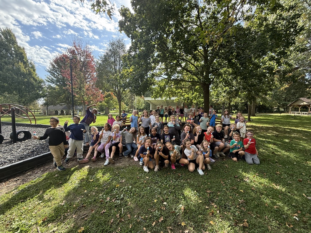 Large group of young students outside with a large tree in the background