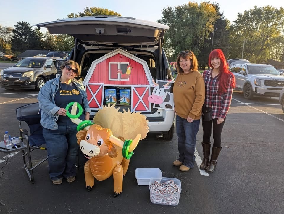 Three woman with an inflatable bow and barn decoration in a trunk