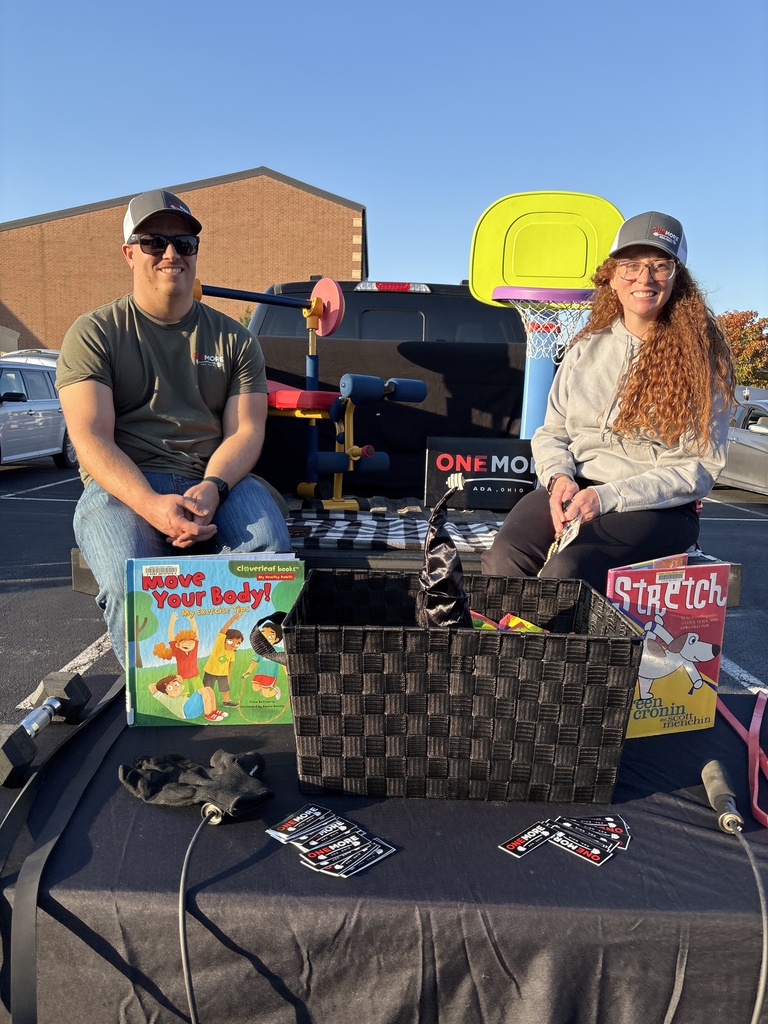 Two people sitting in the tailbed of a truck with a black table in front of them 