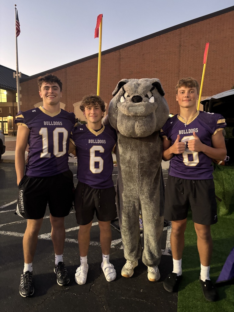 Three students standing with a bulldog costume