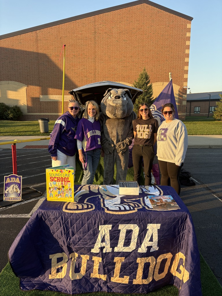 four woman standing with a bulldog costume behind a decorated table