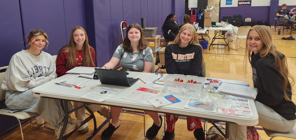 Students sitting at a table with a laptop in front of them and papers to check in guests