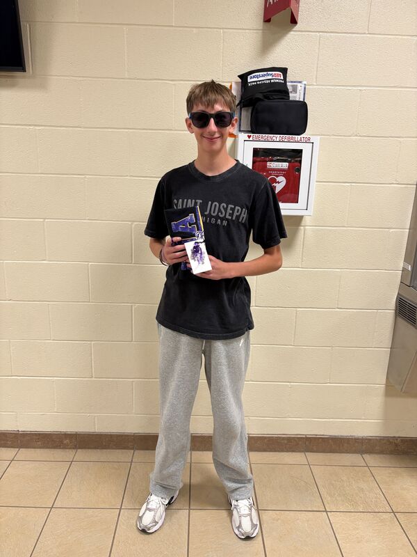 One student wearing sunglasses holding a rolled t-shirt