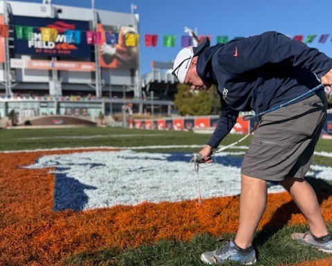 Groundskeeper painting a logo on a football field