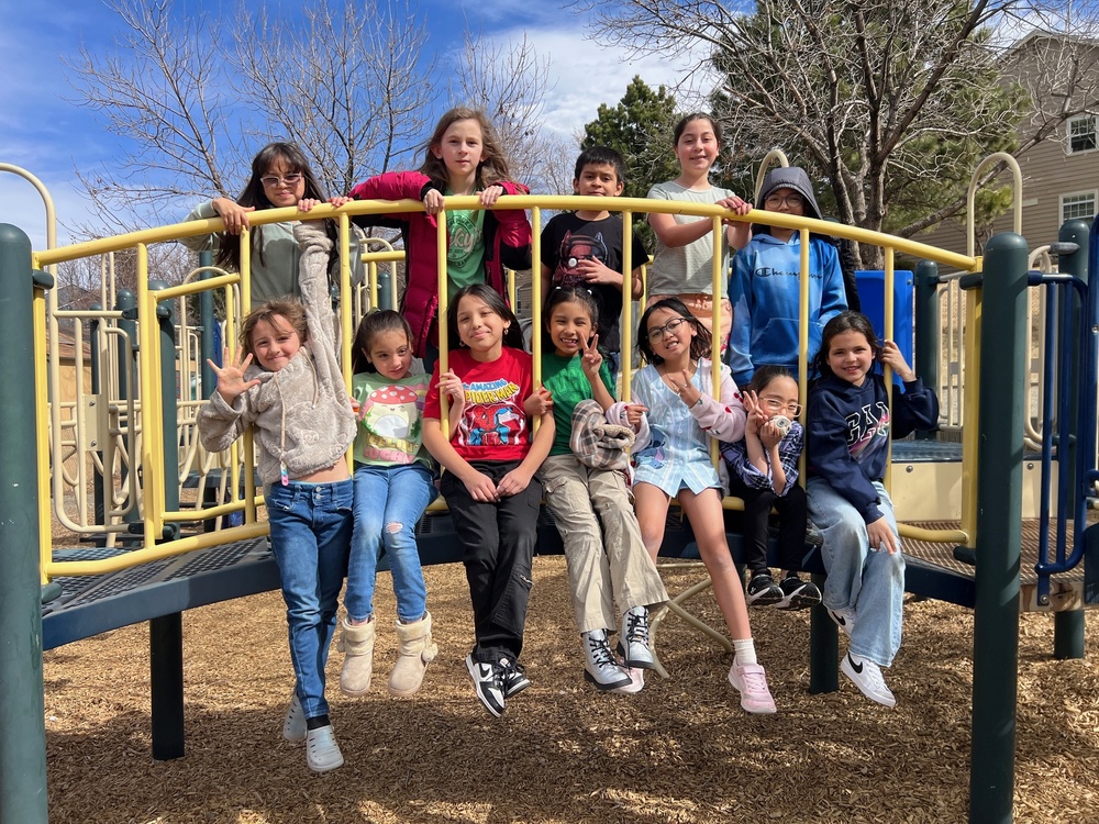 Elementary students smiling on a playground bridge