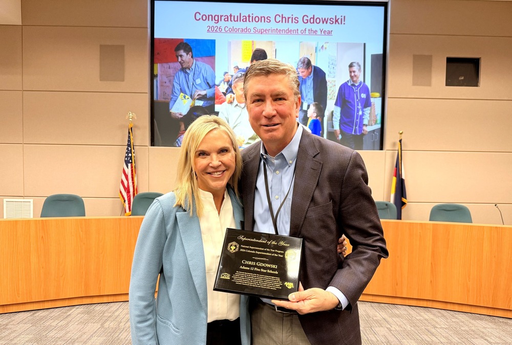 Male and female smiling together holding an award
