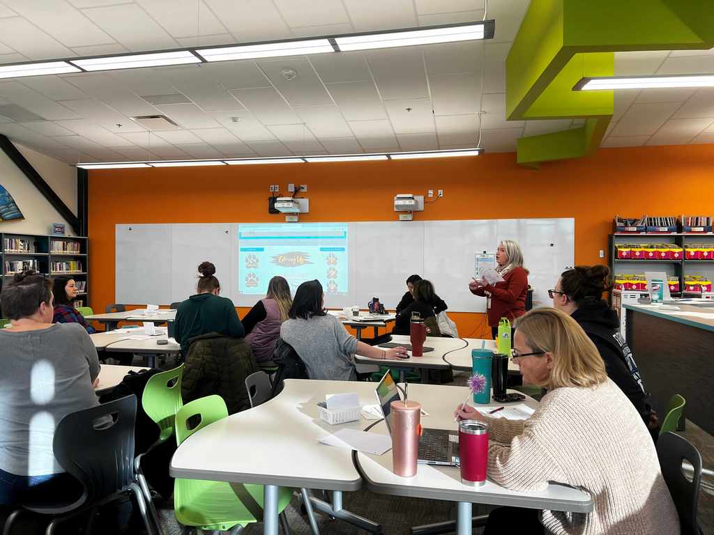 Adults at tables in a school listening to a presentation. 
