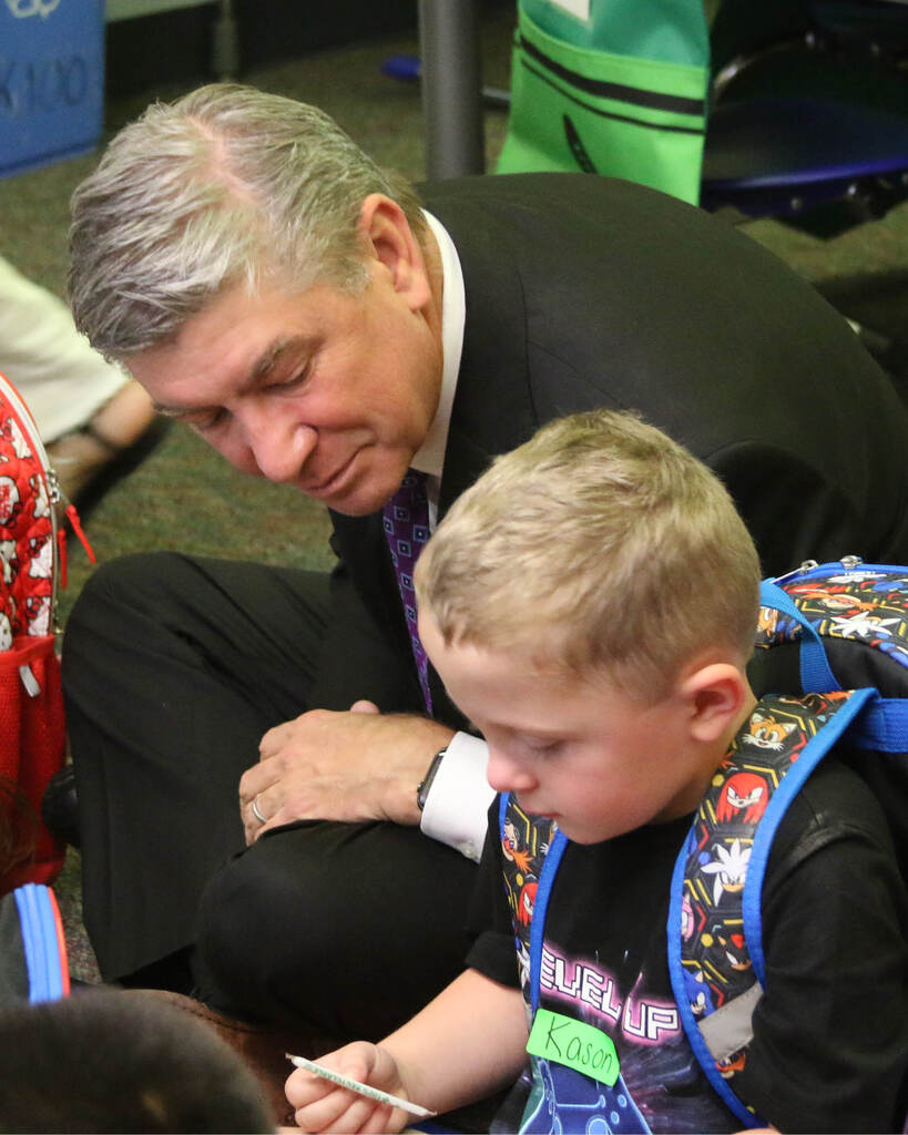 Superintendent sitting with student on the ground