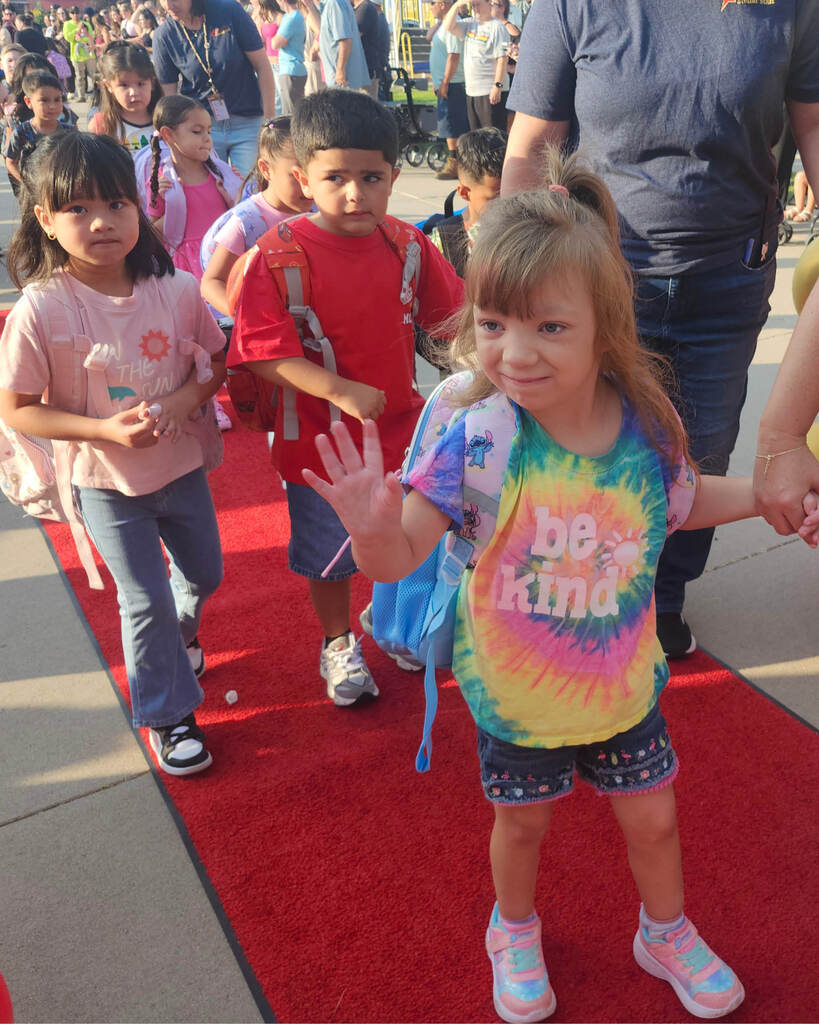 Student waving as she walks the parade 