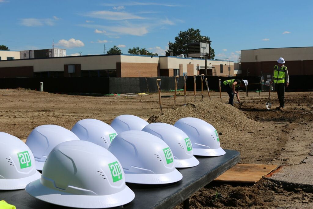 Row of hardhats with shovels in dirt in the background