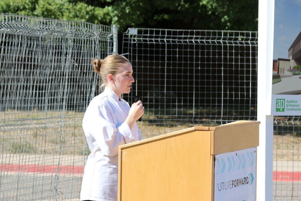 former student speaking at podium