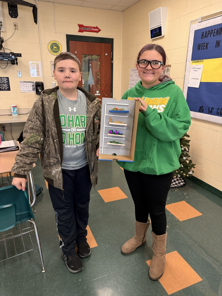 Two students holding their vertical farm model.