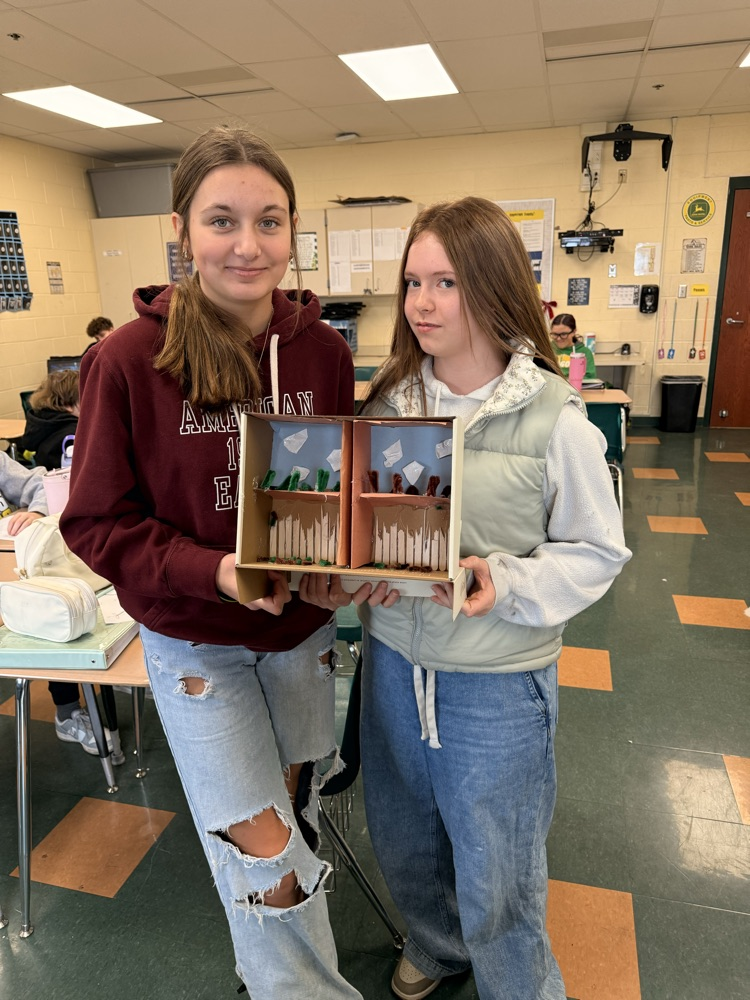 Two students holding their vertical farm model.