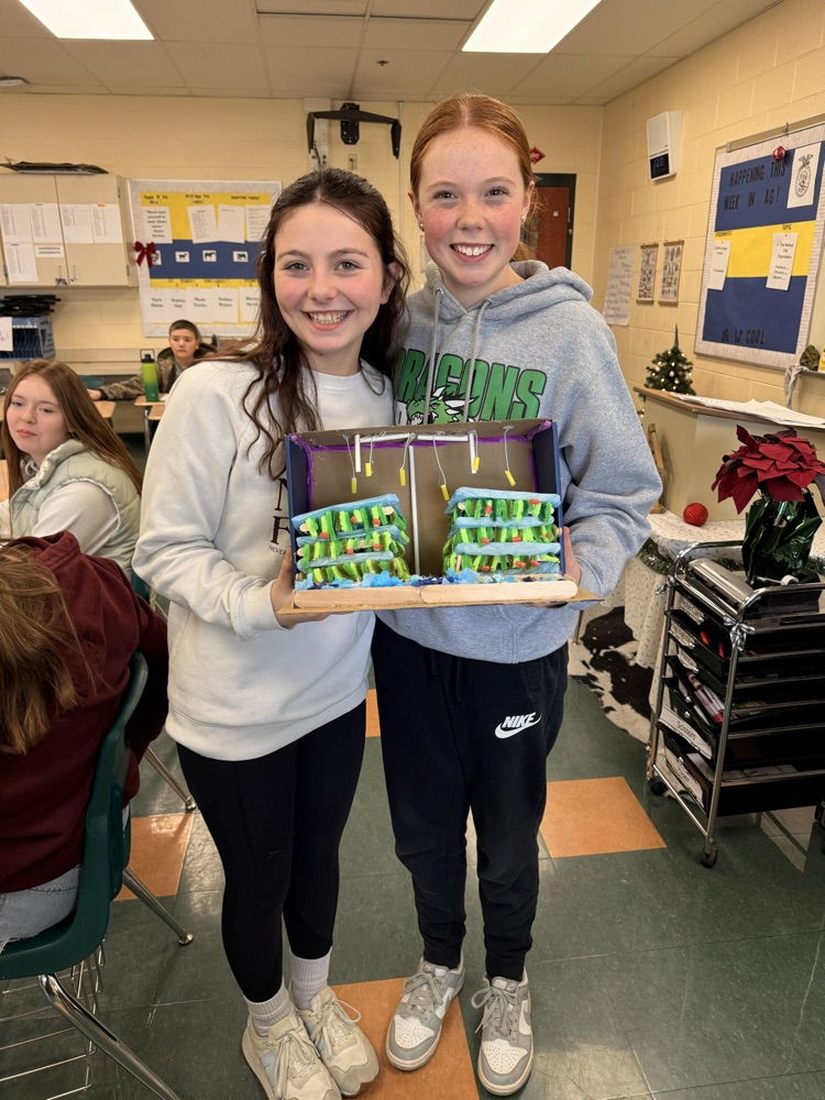 Two students holding their vertical farm model.