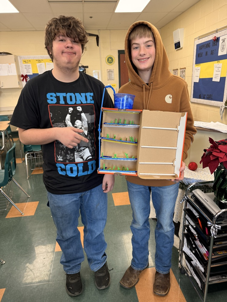 Two students holding their vertical farm model.