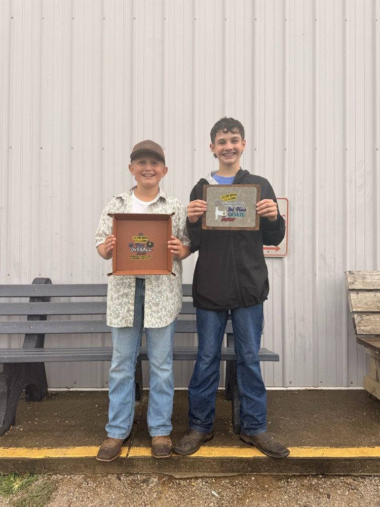 Two young boys standing together with awards. 