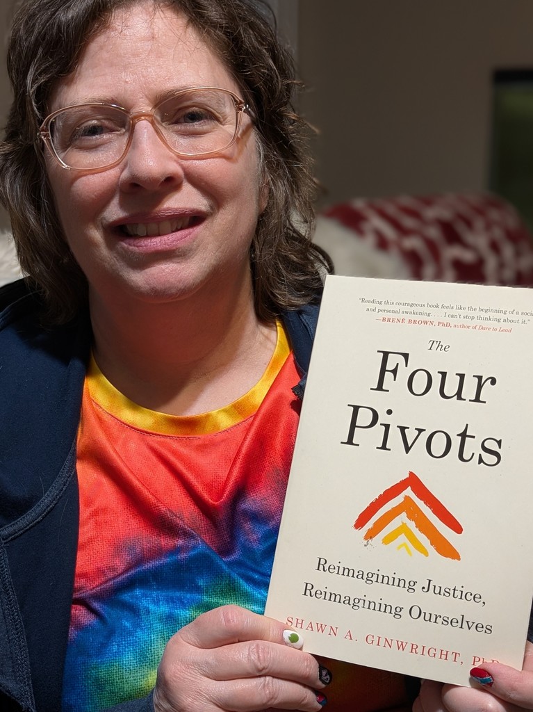 Teacher smiling holding a book called Four Pivots.