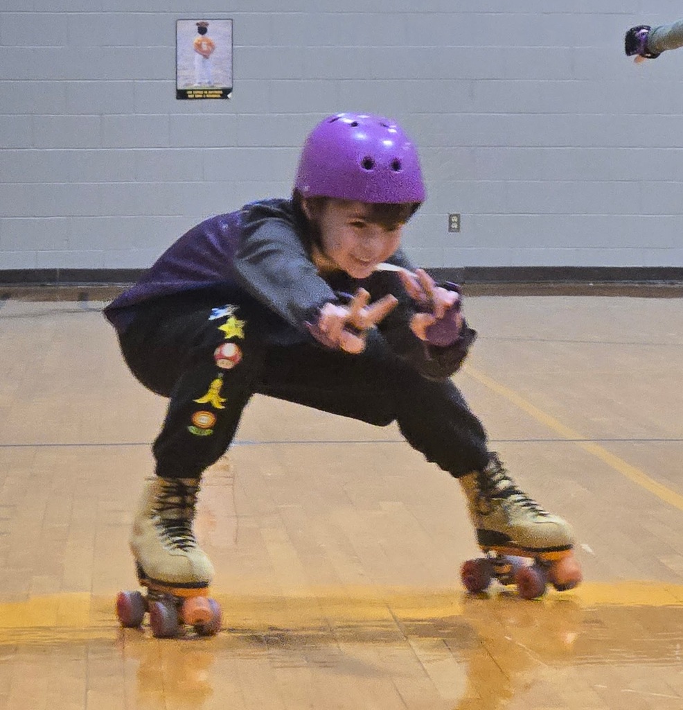 student on roller skates in a sitting positon as a roller skating trick