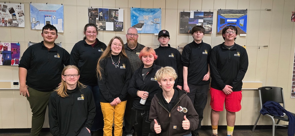 nine students in all black with a teacher posing for picture and smiling