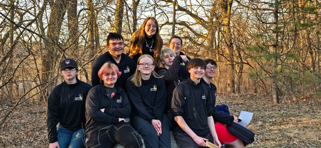 nine students in all black outside posing for picture
