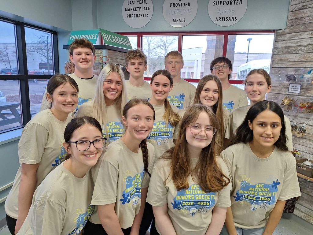 thirteen students in matching tshirts smiling and posing for picture