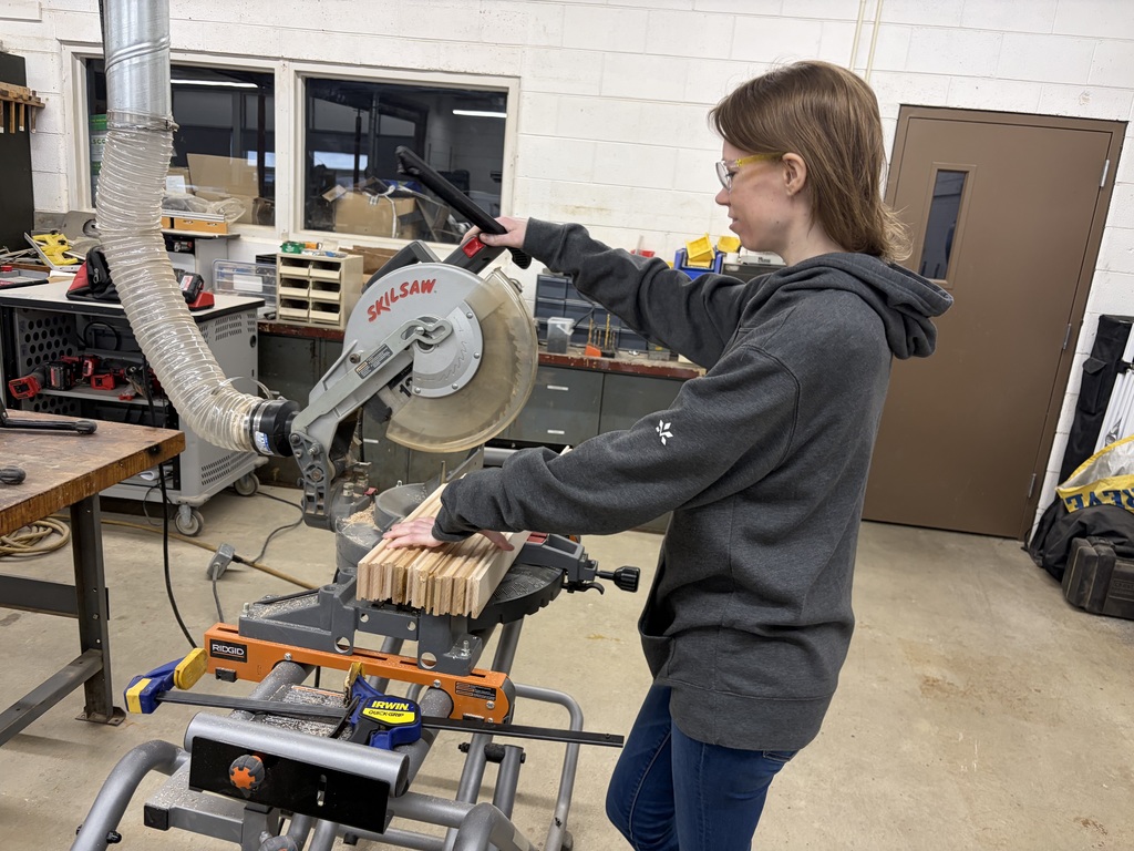 female student using saw to cut wood