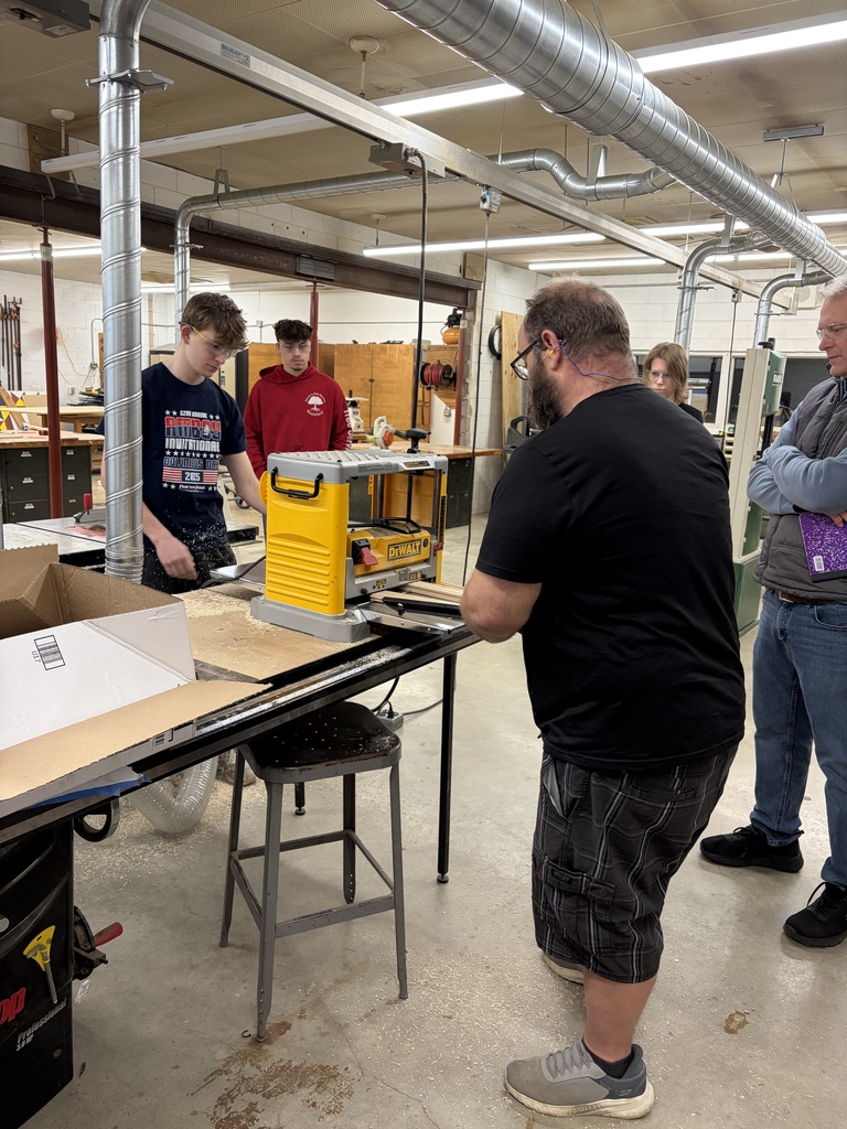 teacher showing high school student how to use a saw wood.