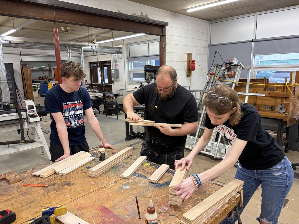 students and a teacher are measuring wood