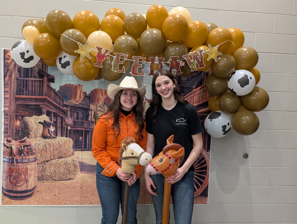 two girls posing in front of country  balloon arch