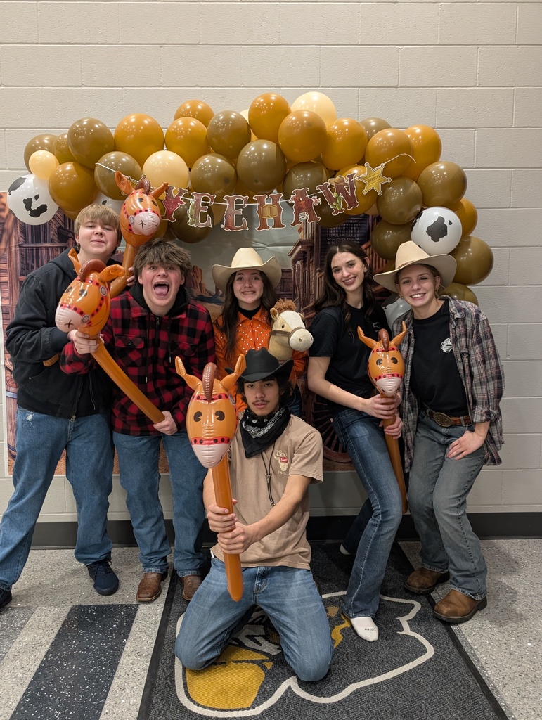 Large group of students  posing in front of country  balloon arch with cowboy hats and inflatable horses