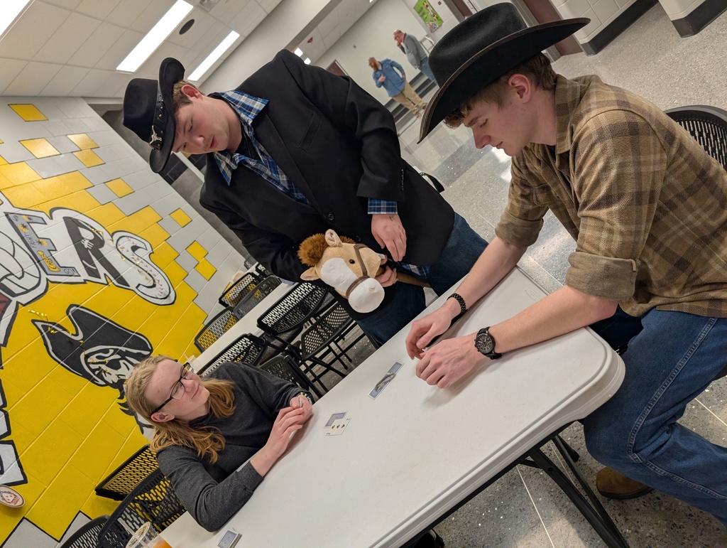 students playing cards at a table, two male students with cowboy hats on