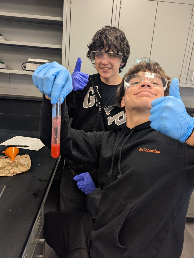 two boys holding test tubes with thumbs up