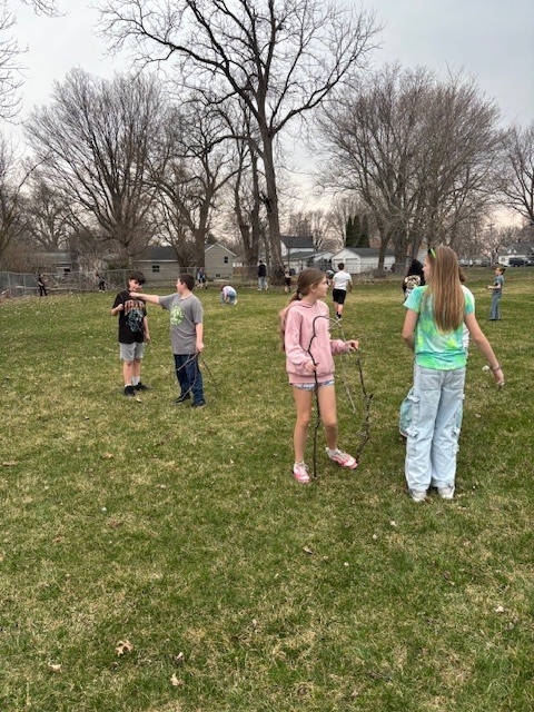 photo of students throughout the grass picking up sticks