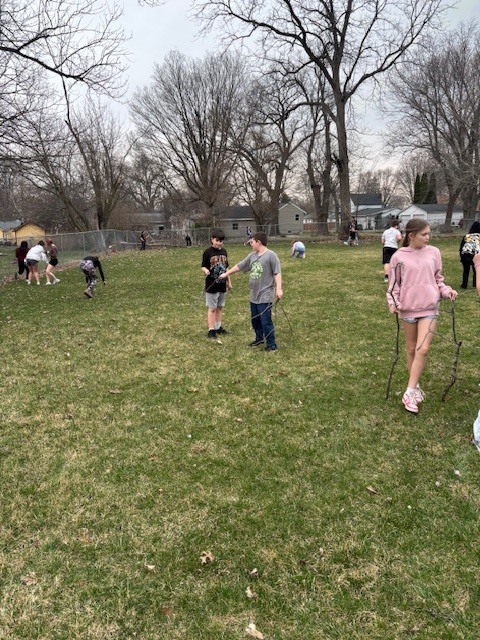photo of students throughout the grass picking up sticks