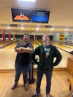 two boys posing in front of bowling lanes