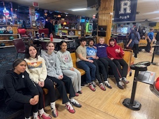 group of students sitting down at bowling alley