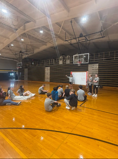 students sitting on gym floor