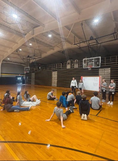 students sitting on gym floor