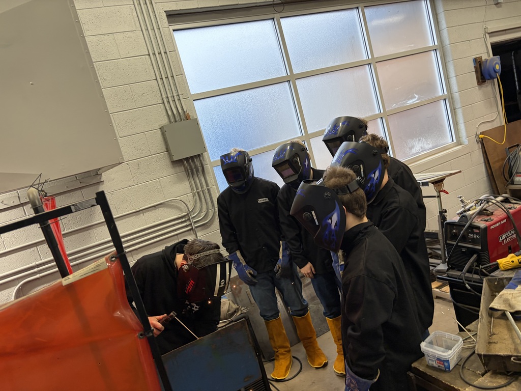 students in welding helmets learning to weld