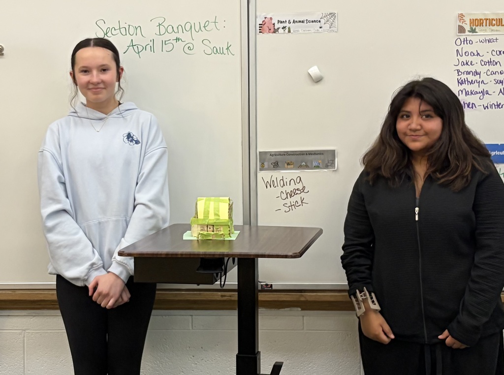 two female students presenting at front of class