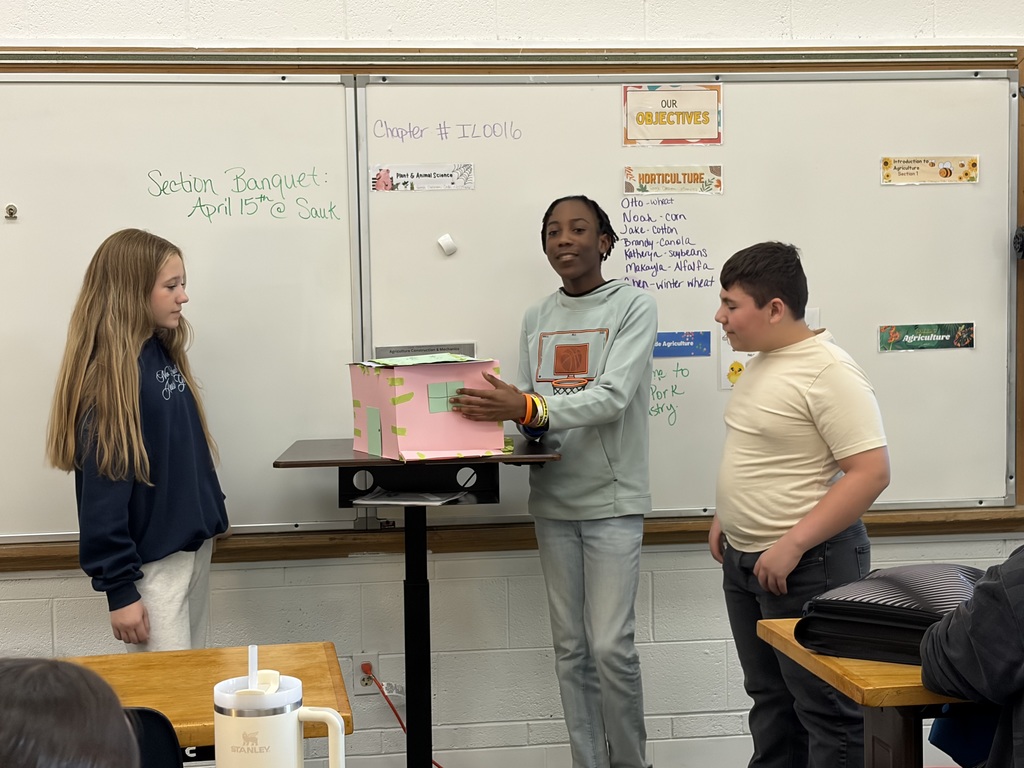 three students presenting at front of class